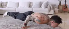 Tattooed man doing pushups on carpet
