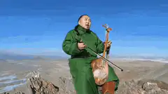Man in green robe playing morin khuur on mountain