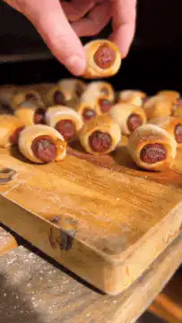 Hand picking up a pig in a blanket