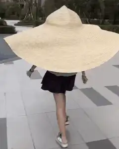 person walking with giant straw hat