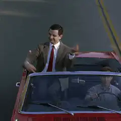 Mr. Bean driving a red convertible