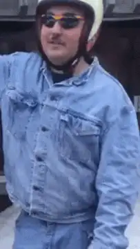 Man in denim jacket and helmet on snowmobile