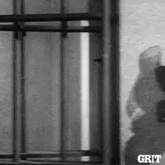 Man in jail cell looking through bars