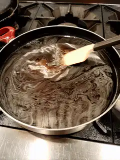 Stirring dark liquid in a pan