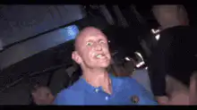 Bald man in blue shirt dancing excitedly