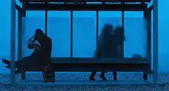 Sad person and kissing couple at bus stop