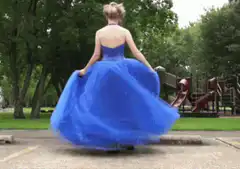 Woman in blue dress twirling in park
