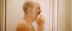 Wet bald man shaving in shower