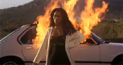 Woman standing in front of burning car