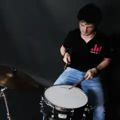 Guy playing drums with text