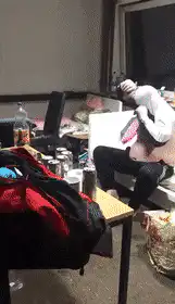 Man puts on shirt while another walks by