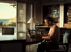 shirtless man typing on laptop