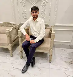 Man in white shirt and plaid pants sitting on ornate chair