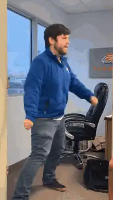 Man in blue jacket dancing in office