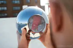 Person holding chrome sphere with cat reflection
