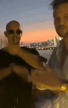 Two men dancing on a rooftop at sunset