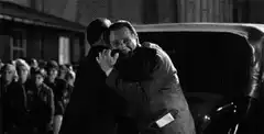 Two men hugging by a car