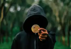 hooded figure holding bitcoin