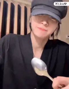Woman in cap holding spoon to camera