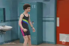 Elton John in a swimsuit flexing