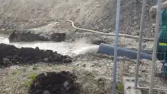 Excavator dumping mud into a pit