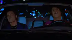 Two men laughing in a car at night