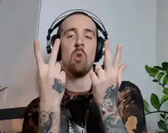 Man with headphones and tattoos doing hand signs