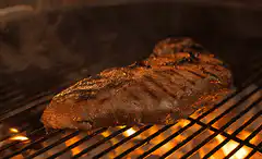 steak grilling over flames
