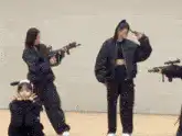 Girls in black holding toy guns dancing