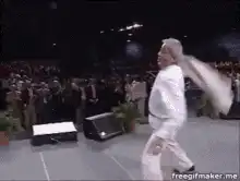 Man in suit dramatically falls backward on stage