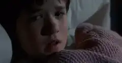 Young boy in bed looking scared