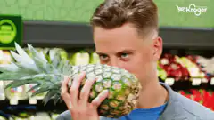 Man smells pineapple in grocery store