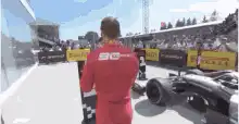 F1 driver walks past cars on grid