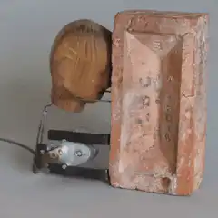 Wooden head shaking no against brick
