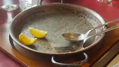 empty paella pan with lemon wedges