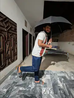 Man holding umbrella indoors with one foot in a high heel