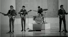 The Beatles perform on stage, cut to shocked man