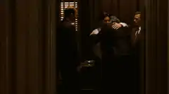 Men in suits hugging in a hallway