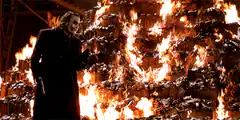 Joker standing in front of burning money