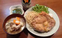 Japanese meal with chicken, noodles, soup, and Sapporo beer