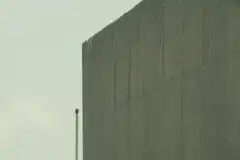 Man peeking from behind concrete wall