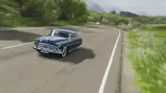 Blue classic car driving on winding road
