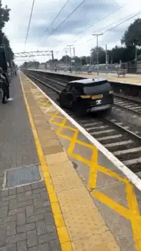 Black car on train tracks at station