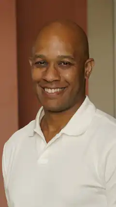 Bald man in white polo smiling