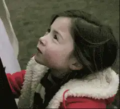 Girl in red coat looks up and smiles