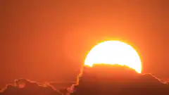 Sun rising behind clouds