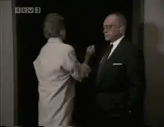 Man in suit turns away in doorway