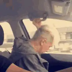 Old man shaking head in car