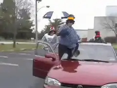 People dancing around a red car