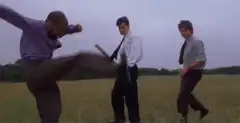 Three men kick a cooler in a field